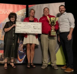 Debi Durham, executive director of the Iowa Economic Development Authority poses with Open 4 Business contest winners, Hardware Hank staff.