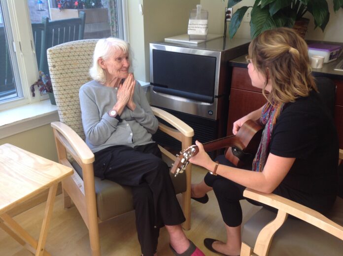 Music therapist Meghan Ross interacts with a resident during a one-on-one music therapy session at Oaknoll Retirement Residence.