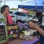 Customer Joni Tibbits of Robins, right, discusses products offered at the Hue Hill stand with vendor Jean Donohue during the Hiawatha Farmers Market on Sunday, May 7. CREDIT CINDY HADISH