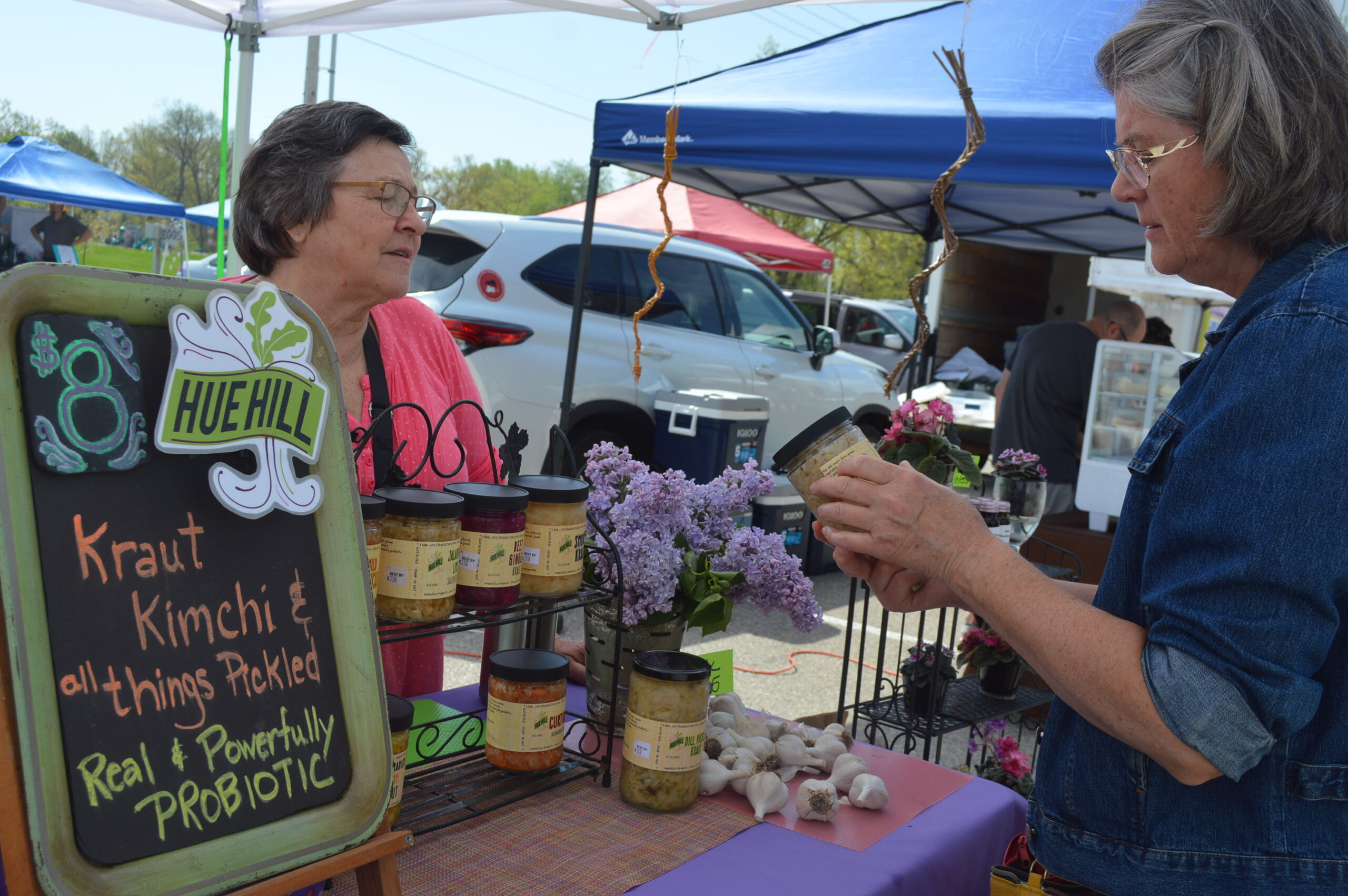 Customer Joni Tibbits of Robins, right, discusses products offered at the Hue Hill stand with vendor Jean Donohue during the Hiawatha Farmers Market on Sunday, May 7. CREDIT CINDY HADISH