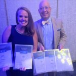 Vice President Aspen Lohman (left) and CEO & President John Lohman (right) display the Corridor Media Group's AABP 2023 Editorial Excellence Awards.