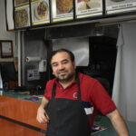 Fawad Nawaz, owner of Hot & Roll, stands at his counter. Hot & Roll is the only Pakistani restaurant in Iowa City. CREDIT ANNIE BARKALOW