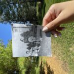 A hand holds a black and white photograph against the current location where the photo was taken.