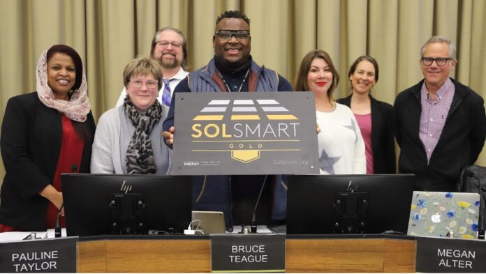 Members of the Iowa City Council display the Gold Level designation plaque from SolSmart.