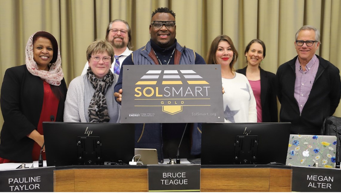 Members of the Iowa City Council display the Gold Level designation plaque from SolSmart.