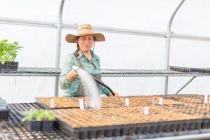 Grow Education and Outreach Coordinator Lisa Stark waters seed trays.