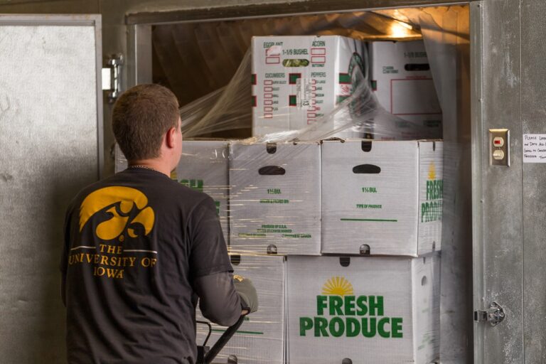A worker loads produce into a refrigerator.