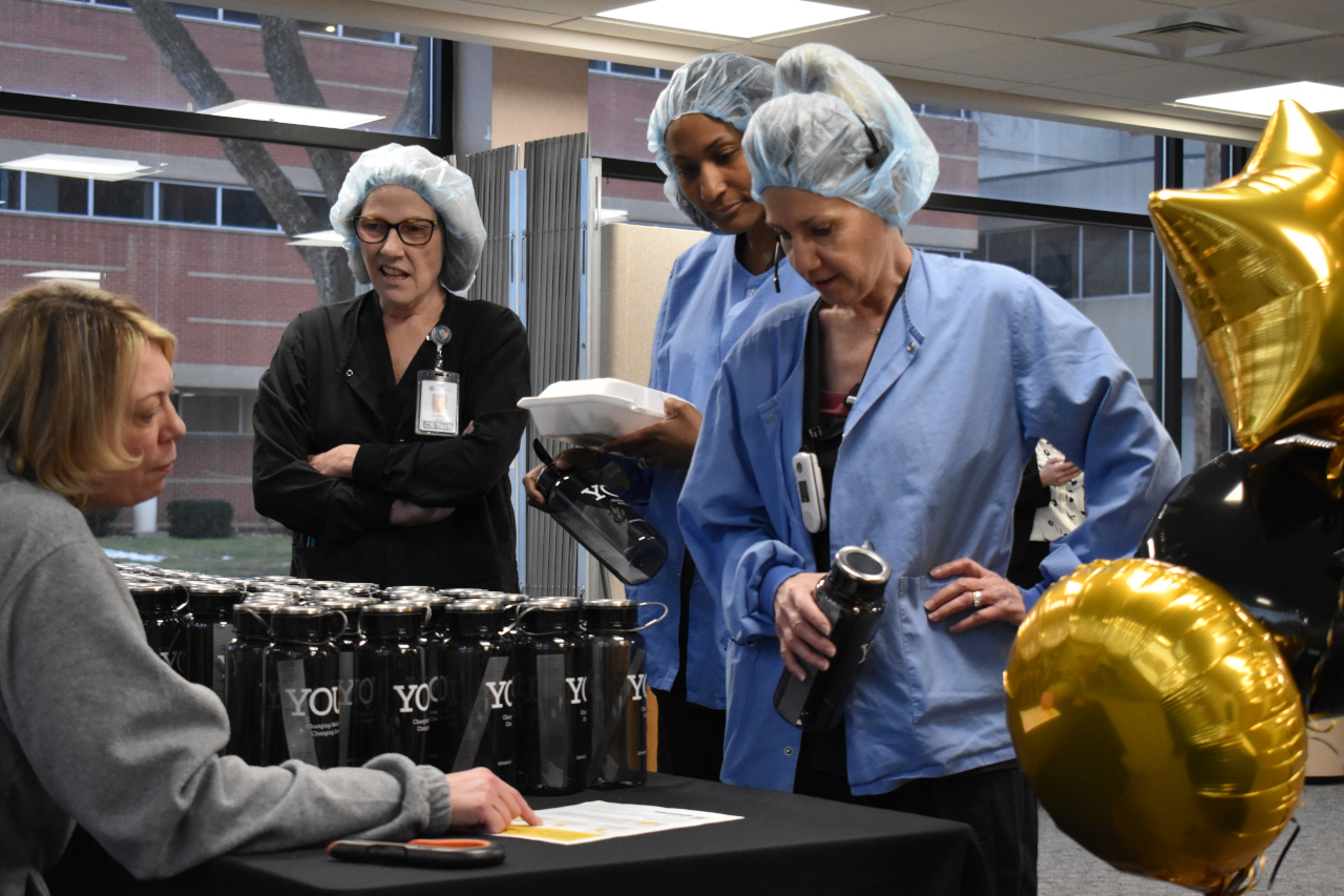 Employees of UI Health Care Downtown Campus eye the water bottles on the table, part of the swag that was offered on the go-live day.