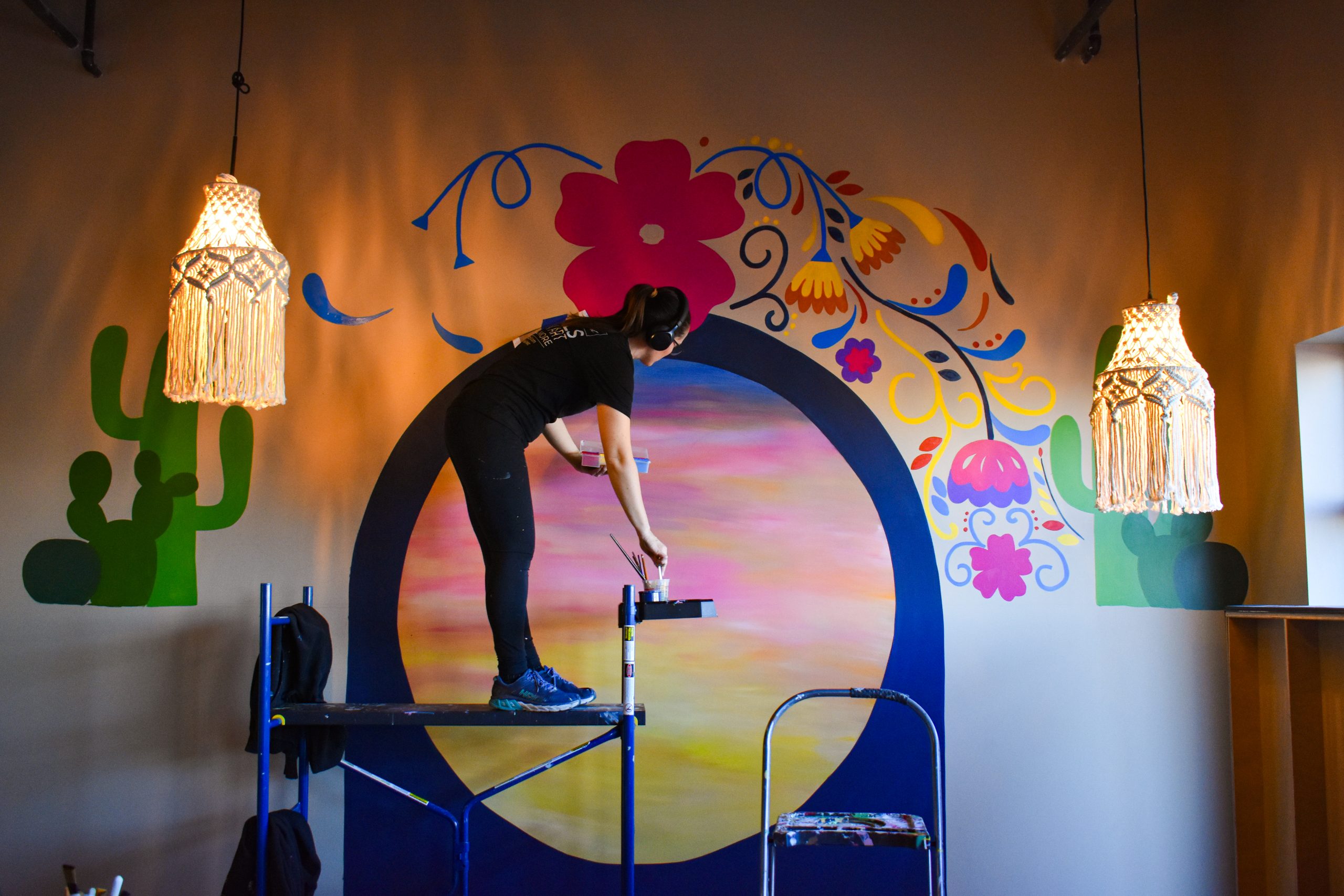 Candice Warby paints a mural at Rio Burritos in Cedar Rapids. Ms. Warby founded her art business, Whimsical Twist, in 2018. CREDIT ALEXANDRA OLSEN