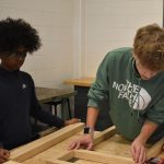 Amjad Ibrahim (left) and Elijah Howe (right), eighth grade Industrial Tech students, fit together pieces of the desk on Friday.