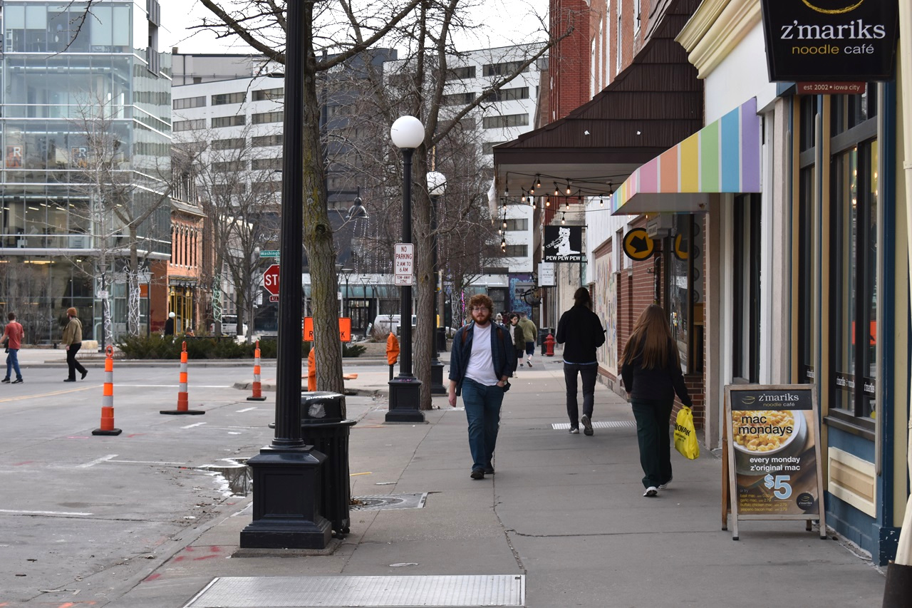 A pedestrian walks the sidewalk on a portion of Dubuque Street in Iowa City. The city and Iowa City Downtown District are partnering to contract Block by Block, a national cleaning firm that specializes in keeping downtown area clean and safe.