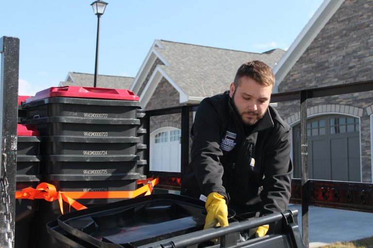 Wesley Smith, owner of Smith Sanitation, takes a moment to adjust a waste bin before setting it on the curb.