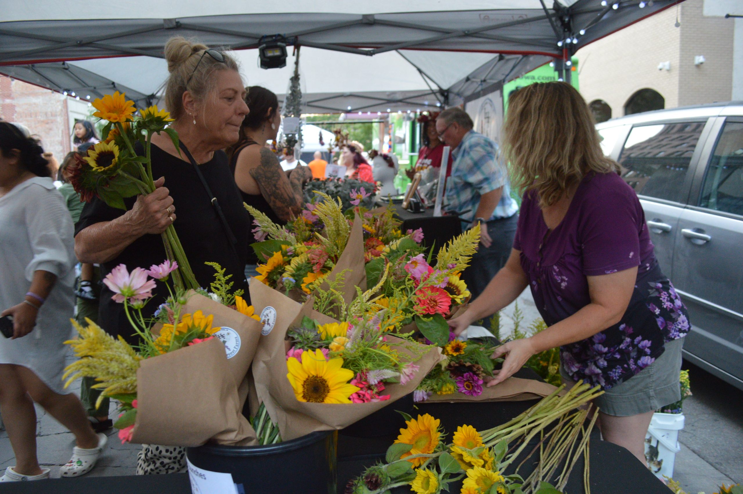 Customers select flowers during last summer's Market After Dark. Part of the Downtown Farmers Market, it will remain at its typical location in downtown Cedar Rapids. CREDIT CINDY HADISH