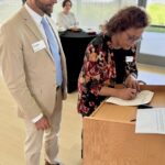 Dan Jansen, Iowa LGBTQ Chamber of Commerce chair, and Dawnelle Conley, SBA deputy district director, sign the strategic alliance memorandum on June 11 in Des Moines.
