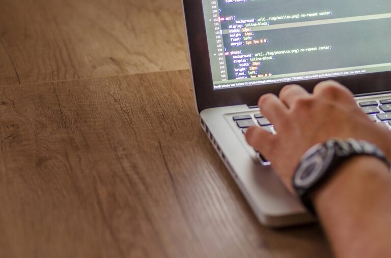 A hand types on a laptop keyboard.
