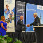 Aspen and John Lohman accept a celebratory trophy at the CBJ's Future of the Corridor event, July 26, 2024. The event celebrated the CBJ's 20th anniversary and featured talks on the region's future.