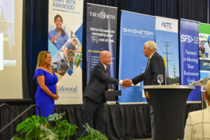 Aspen and John Lohman accept a celebratory trophy at the CBJ's Future of the Corridor event, July 26, 2024. The event celebrated the CBJ's 20th anniversary and featured talks on the region's future.