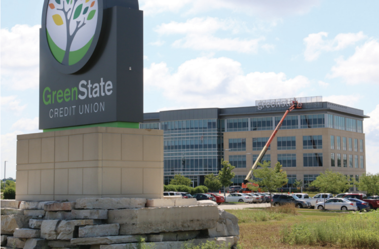 Crews with CR Signs work to install giant letters spelling “greenstate.org” atop GreenState Credit Union’s North Liberty headquarters on July 29, while the refreshed monument sign stands in front. The new signage marks the culmination of GreenState’s transition away from its former name, University of Iowa Community Credit Union, which was forced by a 2018 state law prohibiting credit unions from using the name of any Iowa public university. PHOTO ADAM MOORE