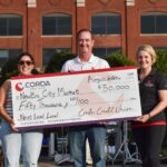 Corda Credit Union representatives present NewBo City Market Executive Director Julie Parisi with a check representing a $50,000 donation to the organization's Next Level Local capital campaign.