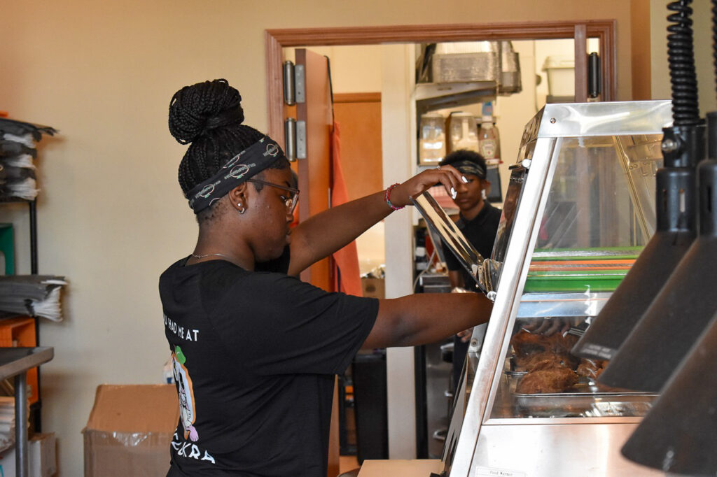 Savannah Dixon, 17, reaches for some fried chicken with a pair of tongs. Ms. Dixon has worked at Sugapeach Chicken & Fish Fry for two years. CREDIT ANNIE SMITH BARKALOW