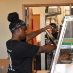 Savannah Dixon, 17, reaches for some fried chicken with a pair of tongs. Ms. Dixon has worked at Sugapeach Chicken & Fish Fry for two years. CREDIT ANNIE SMITH BARKALOW