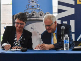 St. Ambrose president Amy Novak and Mount Mercy president Todd Olson sign a "strategic combination" agreement on Thursday, Aug. 1. CREDIT ANNIE SMITH BARKALOW
