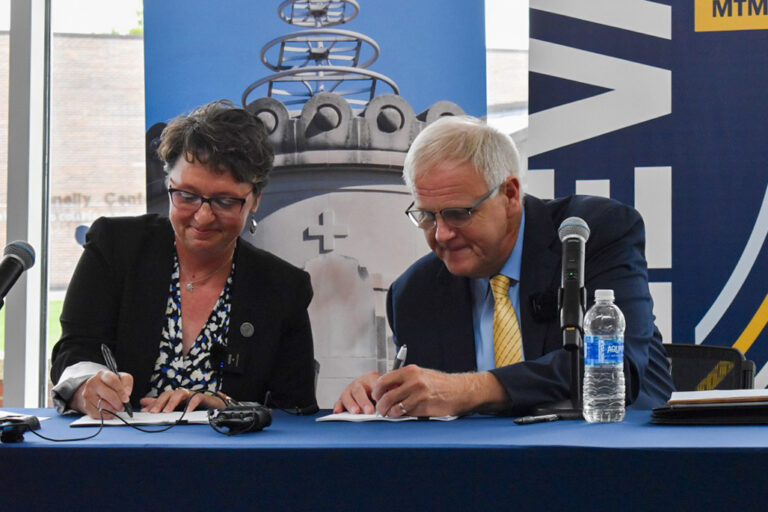 St. Ambrose president Amy Novak and Mount Mercy president Todd Olson sign a "strategic combination" agreement on Thursday, Aug. 1. CREDIT ANNIE SMITH BARKALOW