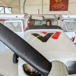 A Coe College student sits in a Revv airplane within a hangar.