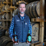 Jamie Siefken, president and general manager of Cedar Ridge Distillery in Swisher, holds bottles of Grit City and Bird Gang bourbon in one of the distillery's barrel sheds. CREDIT RICHARD PRATT