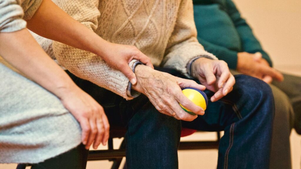 A person places their hand on an elderly man's arm.