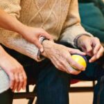 A person places their hand on an elderly man's arm.