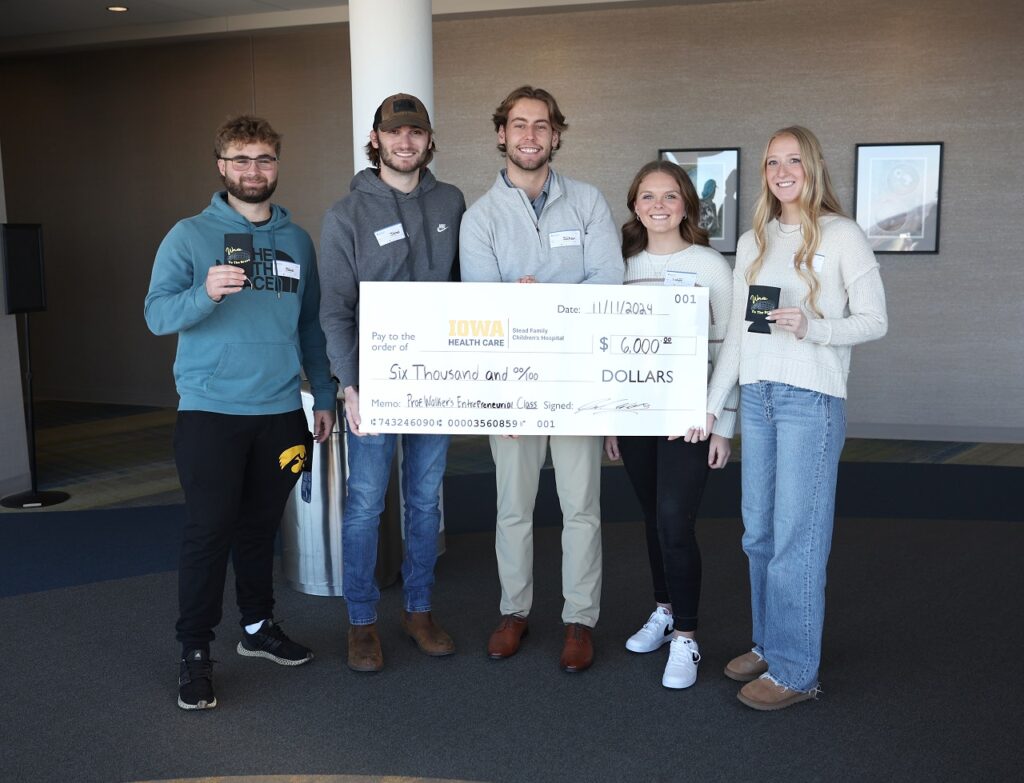 Members of Koozies for a Cause hold up a check for $6,000. The money will be donated to University of Iowa Stead Family Children’s Hospital.