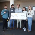 Members of Koozies for a Cause hold up a check for $6,000. The money will be donated to University of Iowa Stead Family Children’s Hospital.