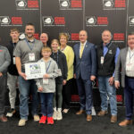 The Ditch Family of Center Point was honored with the Wergin Good Farm Neighbor at the 2025 Iowa Pork Congress in Des Moines. Front left to right: Bob Quinn (Host of The Big Show), Matt Ditch, Joshua Ditch, and Victoria Ditch. Back left to right: AJ Ditch, Ken Ditch, Becky Ditch, Iowa Secretary of Agriculture Mike Naig, Brian Waddingham (Executive Director of the Coalition to Support Iowa Farmers), and Pat McGonegle (Chief Executive Officer of the Iowa Pork Producers Association).