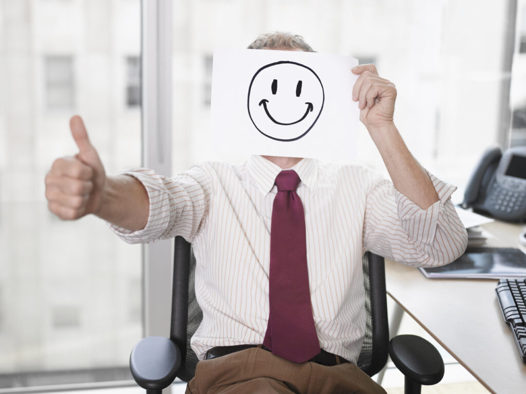 iStock Businessman holding picture of happy face toxic positivity