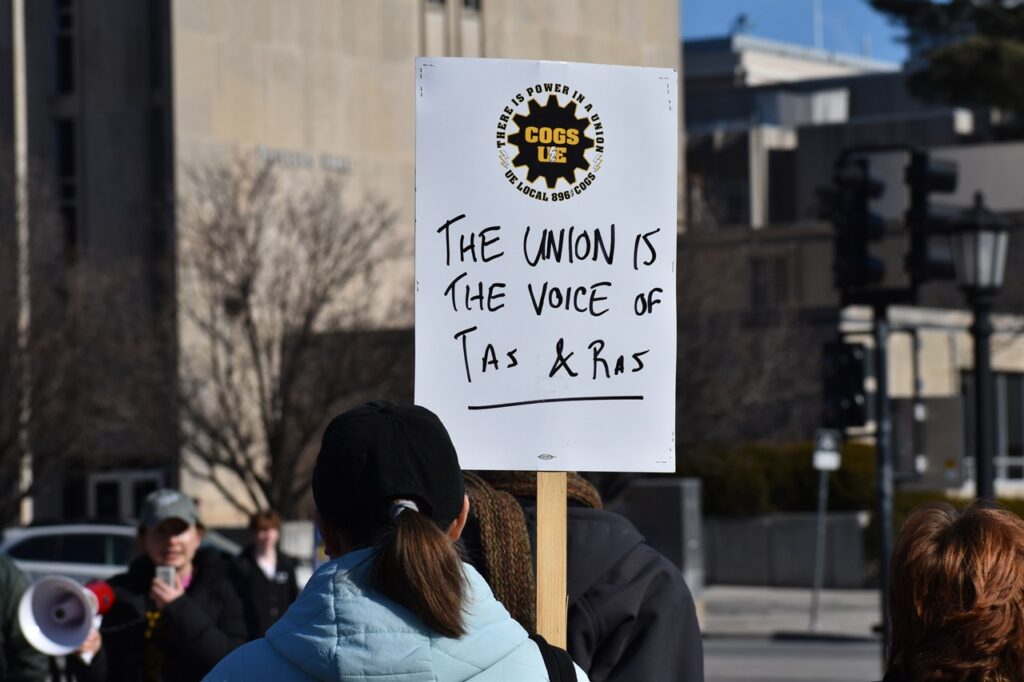 A protestor holds a sign that reads "The union is the voice of TAs & RAs" at the COGS' protest rally Jan. 29 at the Pentacrest on the Iowa City campus.