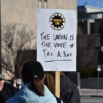 A protestor holds a sign that reads "The union is the voice of TAs & RAs" at the COGS' protest rally Jan. 29 at the Pentacrest on the Iowa City campus.