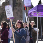 A member of UI Health Care's union SEIU holds a sign that declares "Restore merges staff seniority now!" at the corner of Melrose Avenue and Hawkeye Drive Wednesday. Health care workers say the 3% wage increase offered by the Iowa Board of Regents isn't enough.