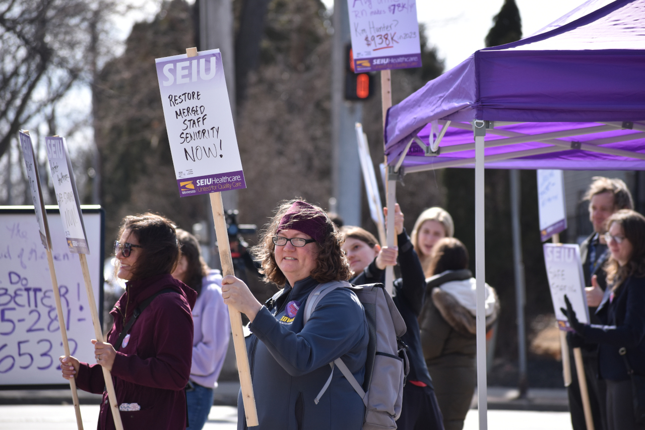 Restore merged staff seniority now A member of UI Health Care's union SEIU holds a sign that declares "Restore merges staff seniority now!" at the corner of Melrose Avenue and Hawkeye Drive Wednesday. Health care workers say the 3% wage increase offered by the Iowa Board of Regents isn't enough.