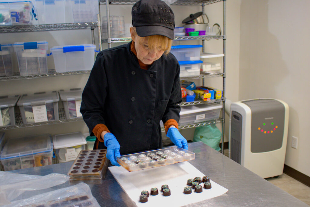 Chocolatier Anne Goddard removes a batch of mint chocolate sweets from a mold at A Chocolate Studio in North Liberty on Feb. 5, 2025. CREDIT PARKER JONES