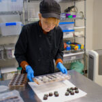Chocolatier Anne Goddard removes a batch of mint chocolate sweets from a mold at A Chocolate Studio in North Liberty on Feb. 5, 2025. CREDIT PARKER JONES