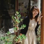 A woman stands outside her shop waiting for customers
