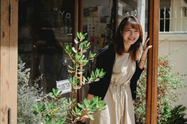 A woman stands outside her shop waiting for customers