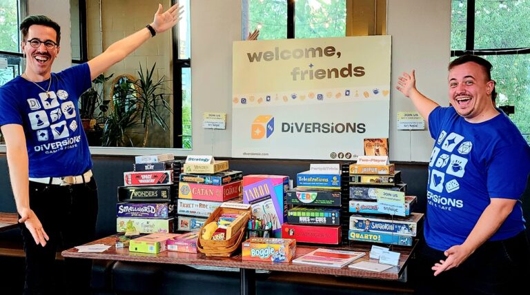 Diversions Tabletop game Lounge co-owners Sean Finn and Nolan Petersen pose next to a stack of board games.