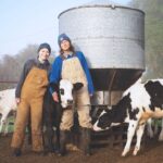 Shae and Anna Pesek of Over the Moon Farm pose with two calves on their farm.