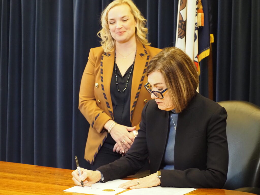 Gov. Kim Reynolds, right, signed an executive order Feb. 10, 2025 establishing the state DOGE task force, joined by Emily Schmitt, general counsel for Sukup Manufacturing Co. who she chose to lead the initiative. (Photo by Robin Opsahl/Iowa Capital Dispatch)