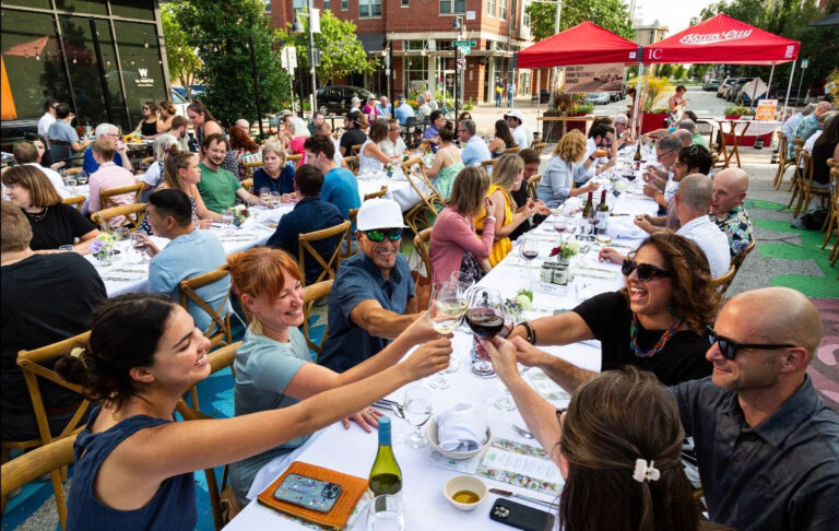 Diners from a past Farm to Street Dinner raise their glasses in a toast.