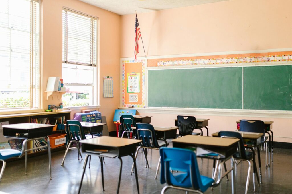 An empty classroom with an American flag hanging in the corner.
