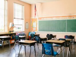 An empty classroom with an American flag hanging in the corner.