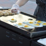 Eggs fry on the grill of Feedwell Kitchen & Bakery during a previous Downtown Farmers Market in Cedar Rapids. Farm-fresh eggs are expected to be in high demand at markets this year. CREDIT CINDY HADISH